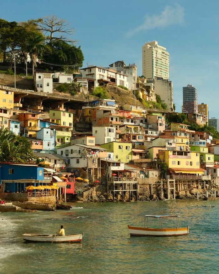 Vibrant hillside favela by the sea with boats in Salvador, Brazil.
