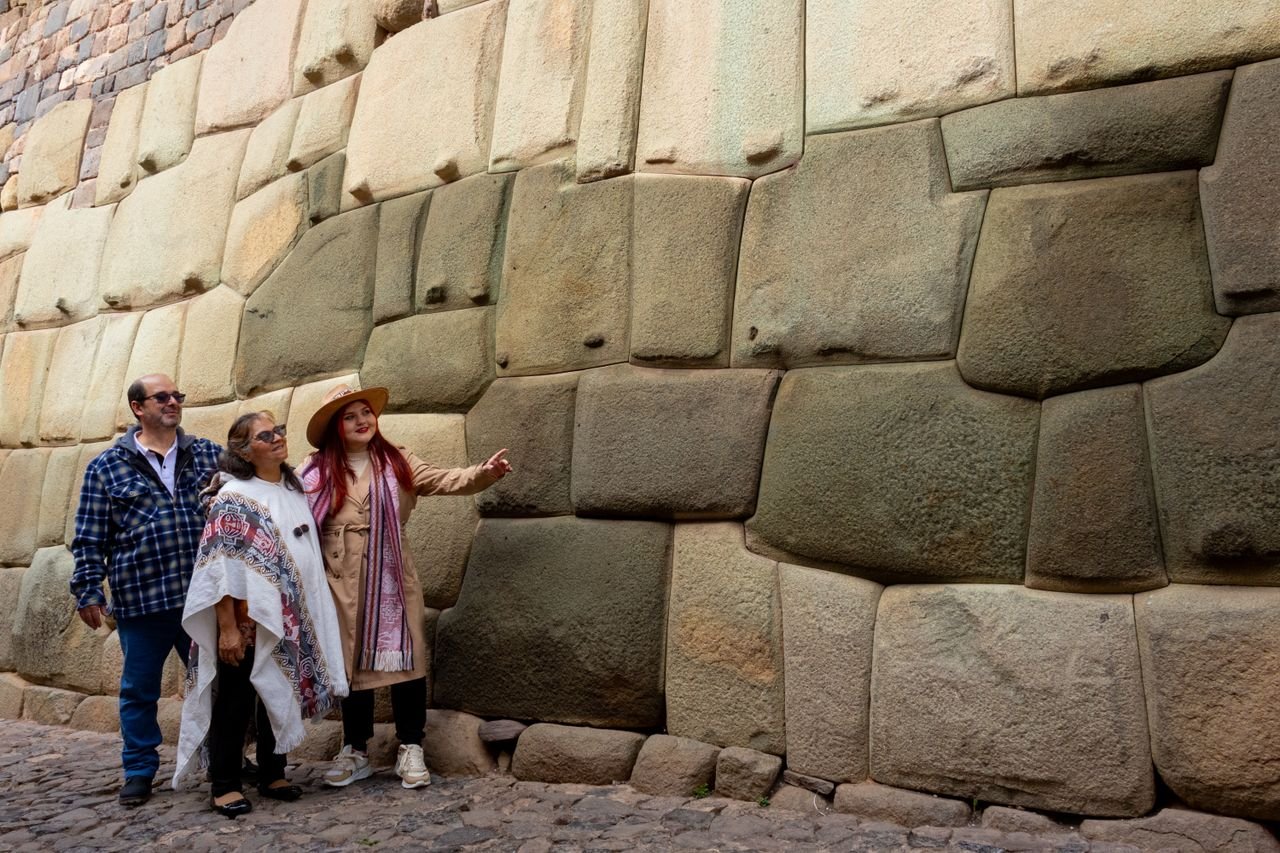 Group of tourists exploring ancient Inca stone wall in Cusco.