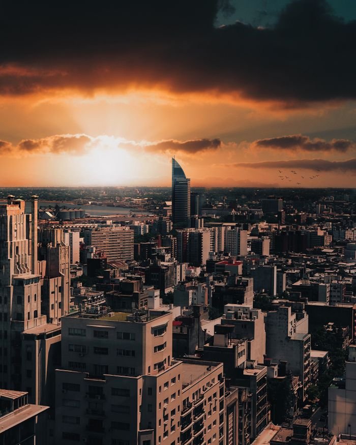 Experience Montevideo's stunning skyline under a dramatic sunset sky, highlighting the city's vibrant architecture.