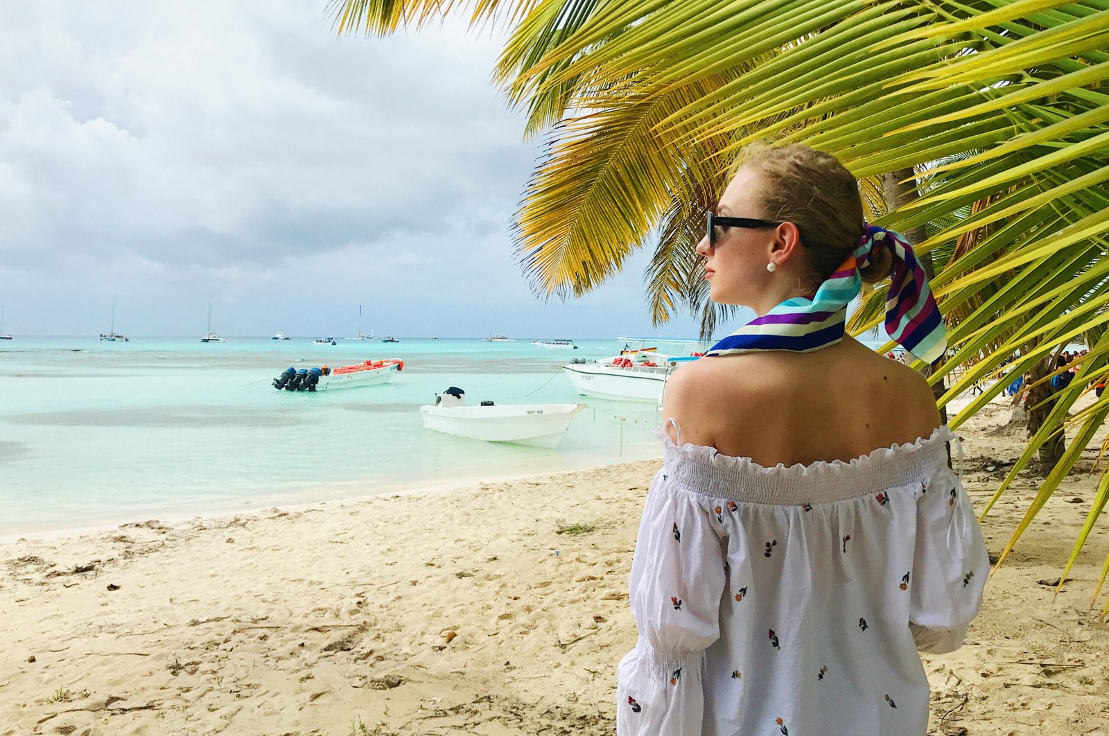 stunning woman in white shirt stands under the palm